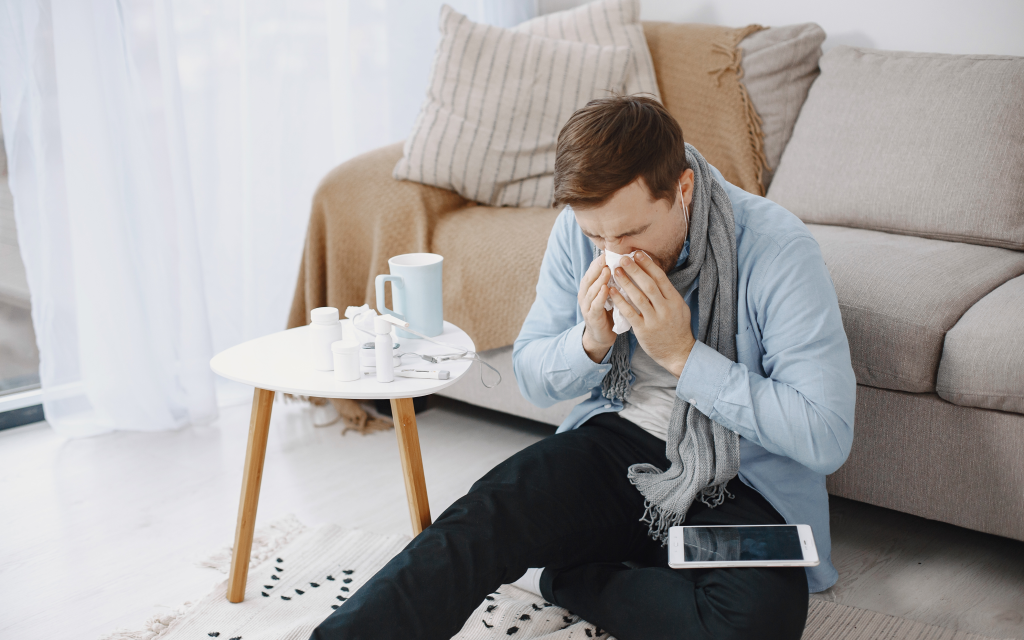 A man sneezing due to the allergens in his house