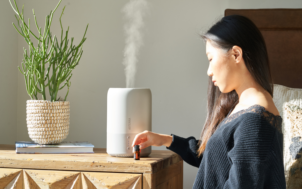A lady using a humidified to control the humidify in her room and keep it smelling fresh.